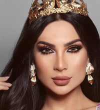 Woman wearing a gold crown and earrings against a gray background. Bella Glow Glow Radiant Hazelnut.