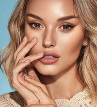 Close-up of a woman with blonde hair and beige sweater against a blue. Bella One Day Ash Brown.