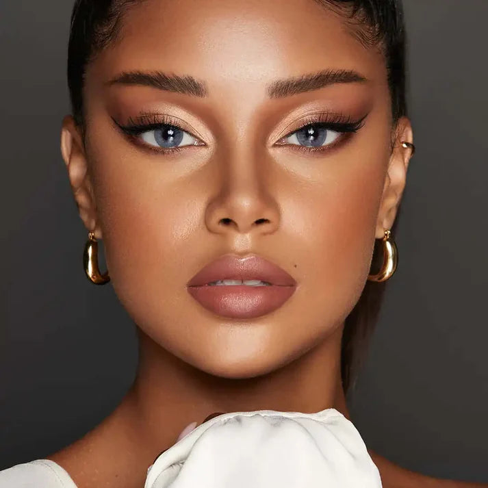 Close-up of a person with makeup and jewelry against a dark background. Bella One Day Bluish Grey