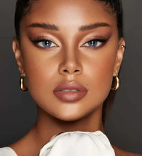 Close-up of a person with makeup and jewelry against a dark background. Bella One Day Bluish Grey