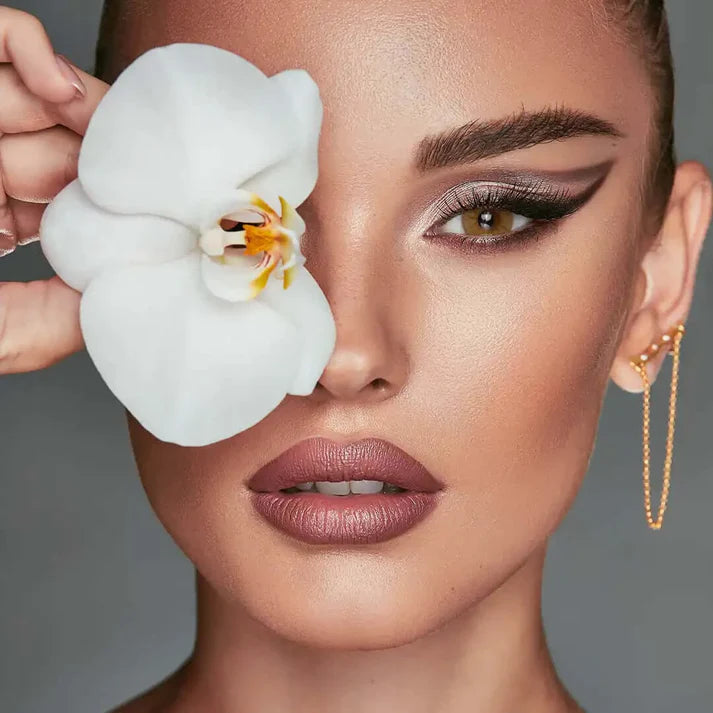 Woman holding a white orchid flower near her face against a gray. Bella One Day Citrine Crystal background