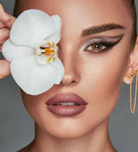 Woman holding a white orchid flower near her face against a gray. Bella One Day Citrine Crystal background