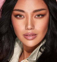 Close-up of a person with dark hair and makeup, wearing a light-colored shirt. Bella One Day Hazel Beige