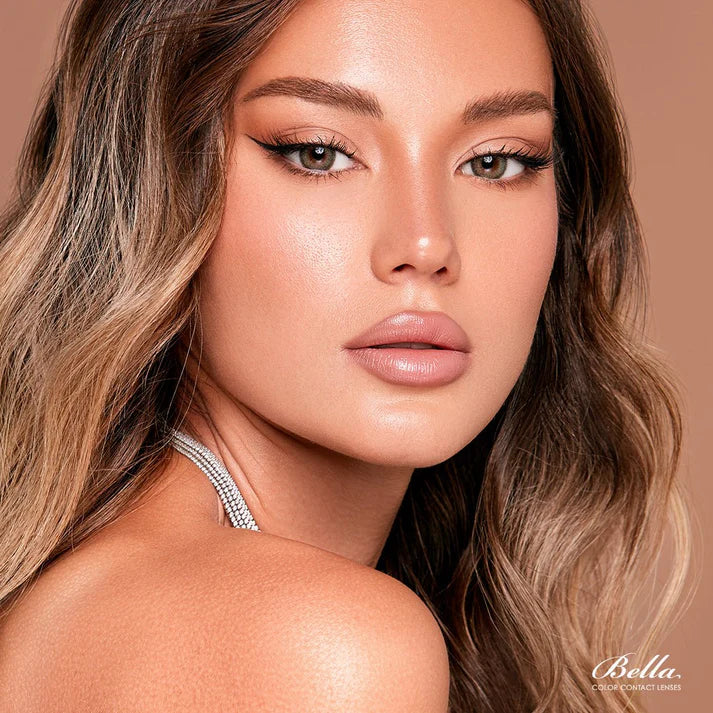 Close-up of a woman with styled hair and makeup on a brown background, featuring the brand 'Bella'.
