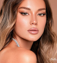 Close-up of a woman with styled hair and makeup on a brown background, featuring the brand 'Bella'.
