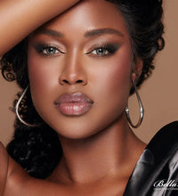 Woman with hoop earrings and a black garment on a beige background. Bella One Day Pine 3